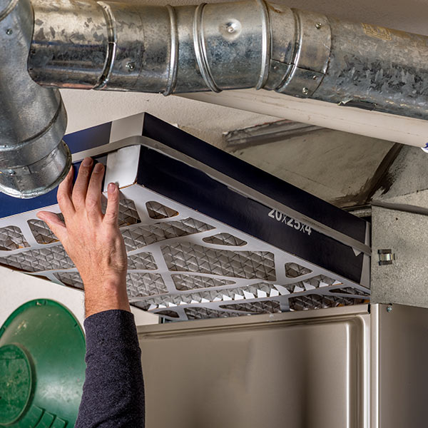 Man replaces a filter in a furnace