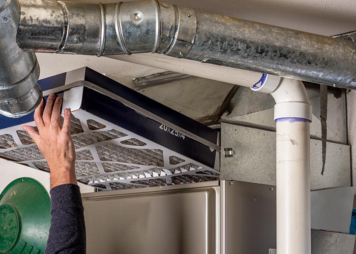 Expert technician from Air Tech Heating & Air Conditioning Service Co. replacing a furnace filter
