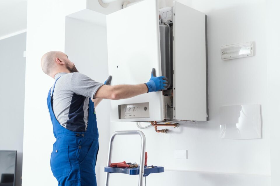 Professional servicing a wall-mounted boiler with tools in San Joaquin County