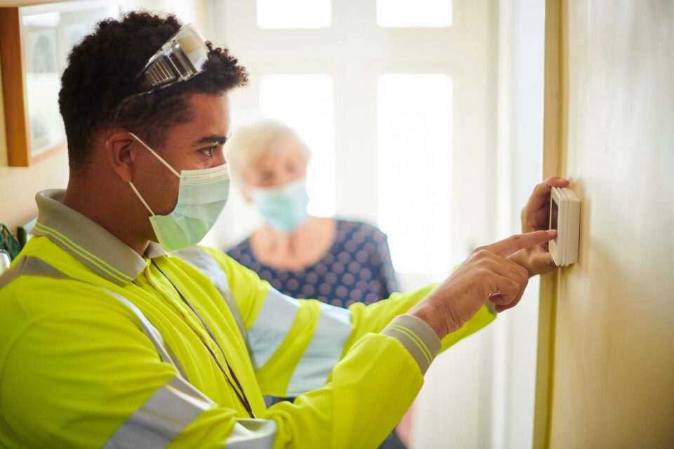 Technician in high-visibility jacket adjusting a wall-mounted control panel in San Joaquin County