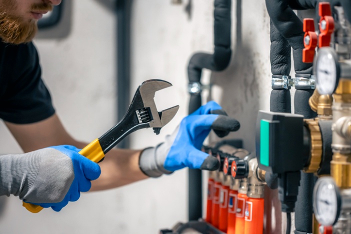 Technician adjusting valves on heating system using wrench and gloves in San Joaquin County