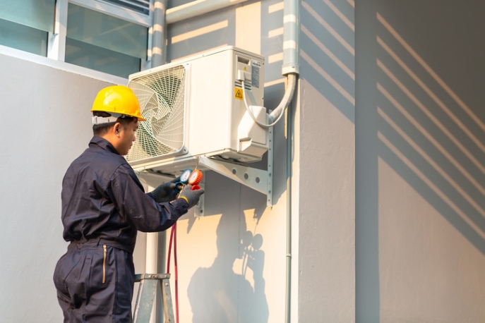 HVAC technician checking outdoor air conditioning unit with pressure gauge in San Joaquin County