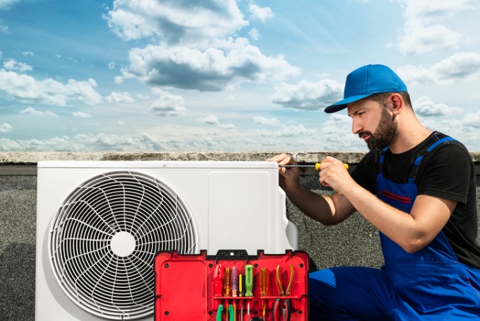 AIR TECH Heating & A/C Service Company technician repairing an outdoor air conditioning unit