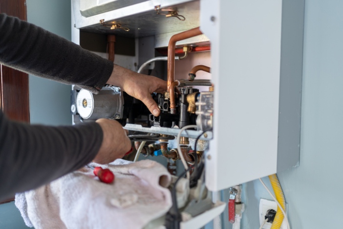 Technician repairing internal components of wall-mounted heating unit in San Joaquin County